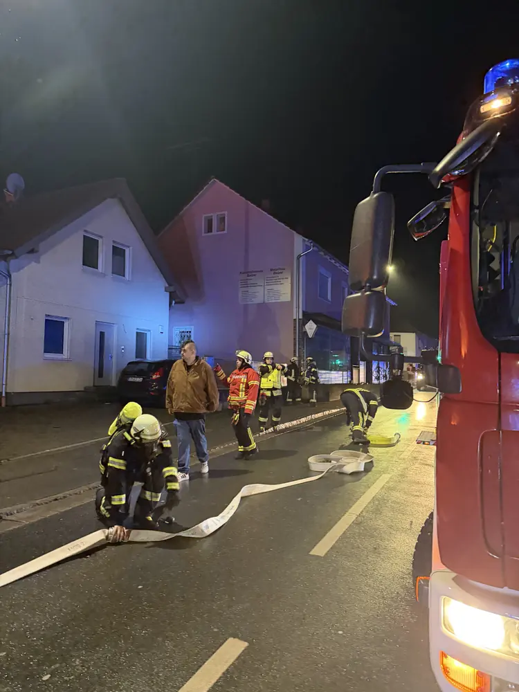 Feuerwehrkräfte und Einsatzfahrzeug bei einem nächtlichen Einsatz